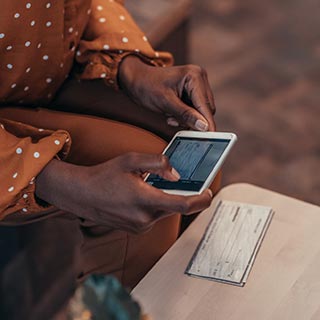 Woman's hands taking photo of check with smart phone.