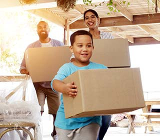A young boy and his parents are happily carrying move-in boxes. 