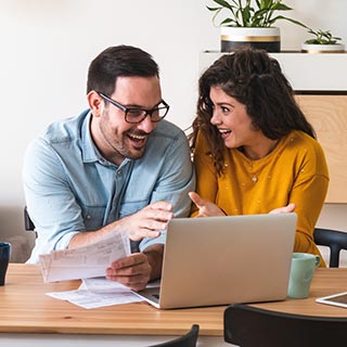 Couple with paperwork in front of laptop at home.