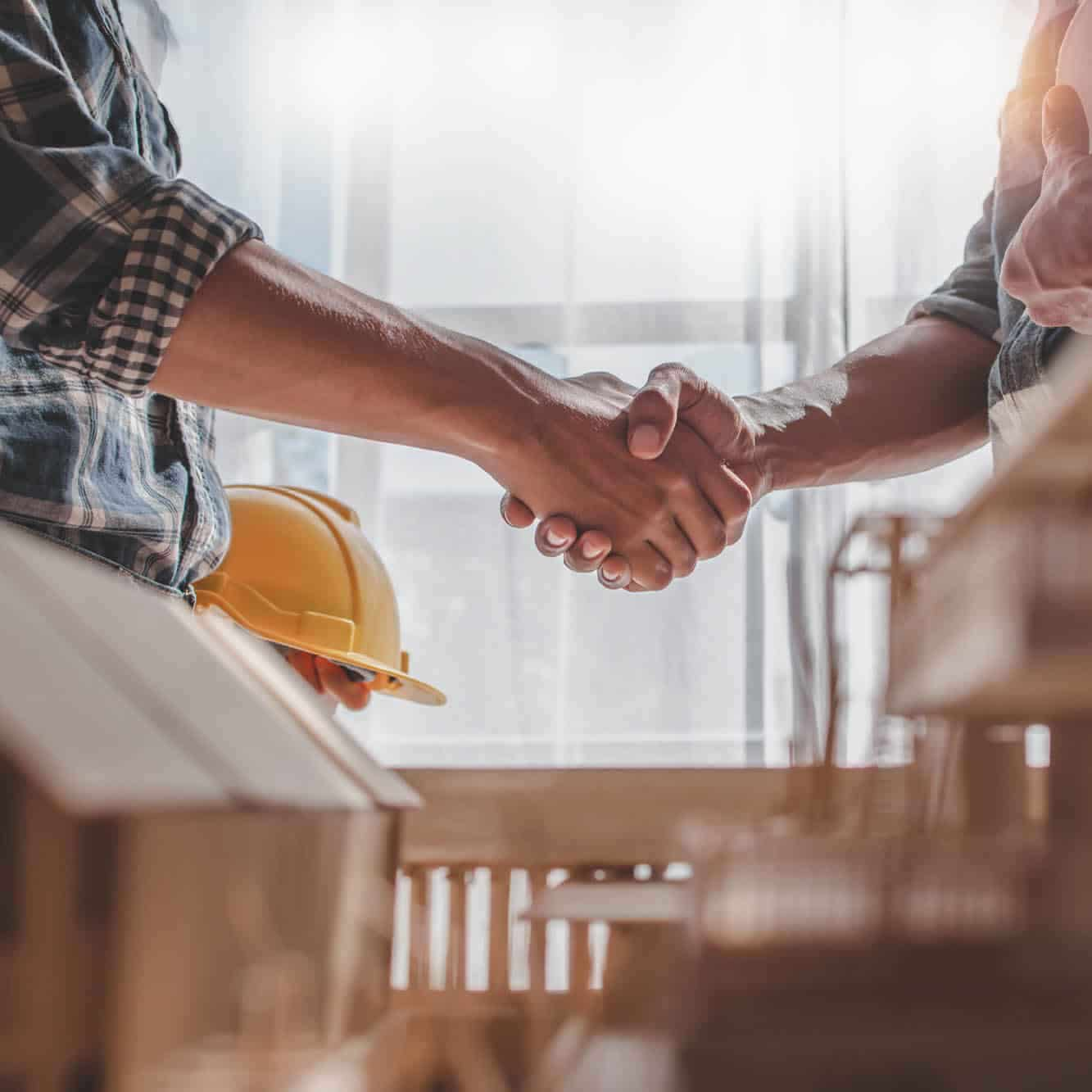 Two men are shaking hands in a construction zone. 